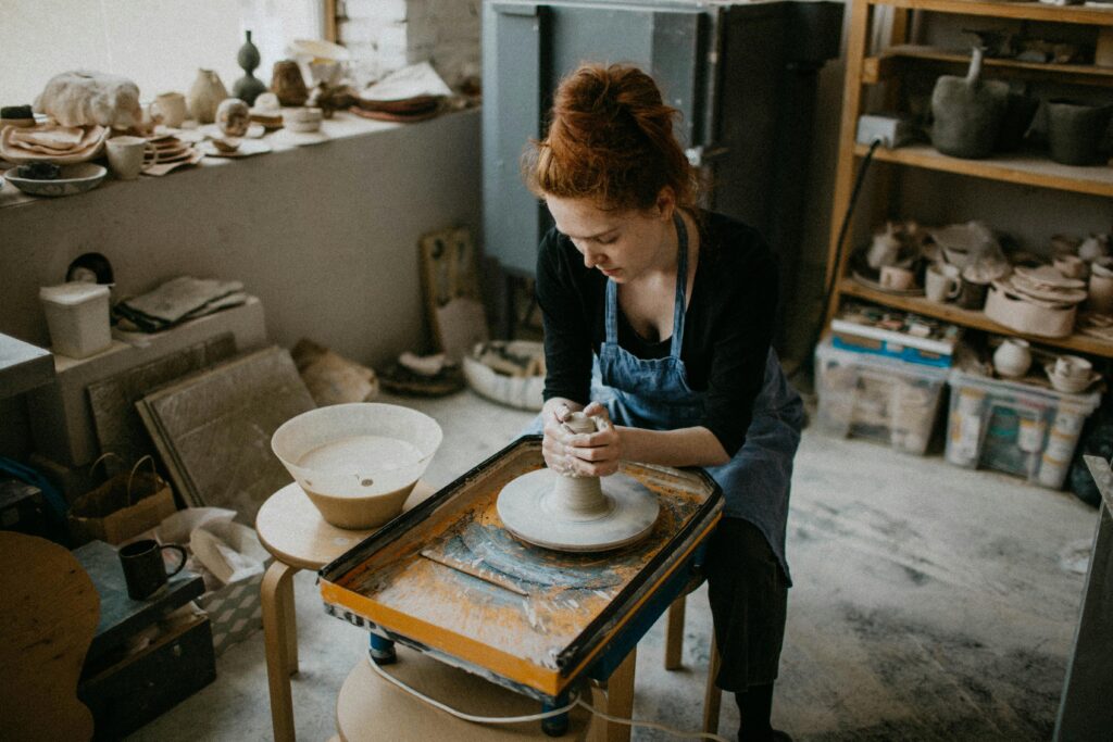 pexels-photo-3094225-3094225 A skilled woman shapes a clay pot in an artistic pottery studio.